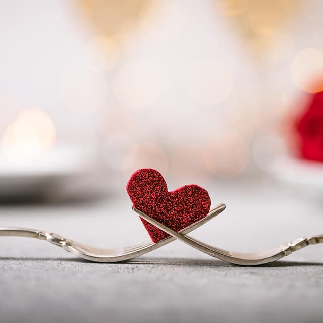 Menu Saint valentin Deux fourchette se croisant avec un cœur en arrière plan